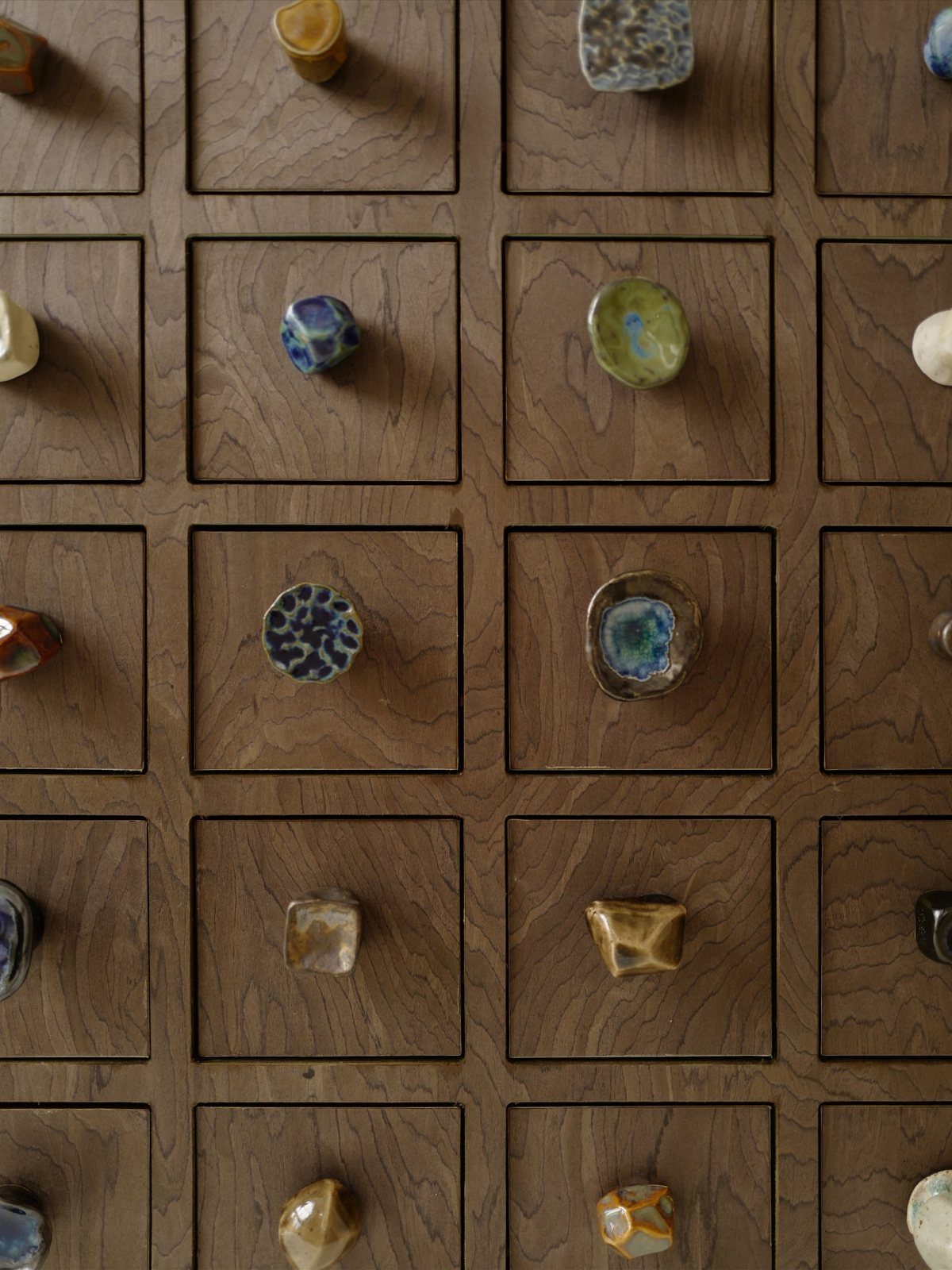 12 Kitchen Cabinet Handles Ideas to Refresh Your Space 12 Handcrafted ceramic knobs in various colors and shapes on small wooden drawers.